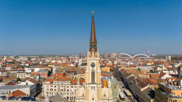 Aerial view of the Name of Mary Church's striking spire piercing the clear blue sky, contrasting against the city's terracotta rooftops, Sad, Vojvodina, Serbia.