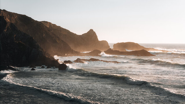 Aerial view of rugged cliffs meet the turbulent sea at Praia da Am&Atilde;&iexcl;lia, where golden sunlight casts long shadows on the rocks, Cabe&Atilde;&sect;o da Arv&Atilde;&copy;loa, Beja, Portugal.