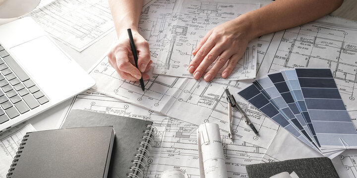 Sustainable architecture workspace with solar panel sample, blueprints, laptop and rolled plans, renewable energy and green building design, engineering and project planning concept.