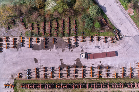 Olaberria, Spain - 09 March 2026: Aerial view of a truck amidst rows of orange trailers, a stark contrast to the surrounding greenery, concrete, and rust-colored metal stacks.