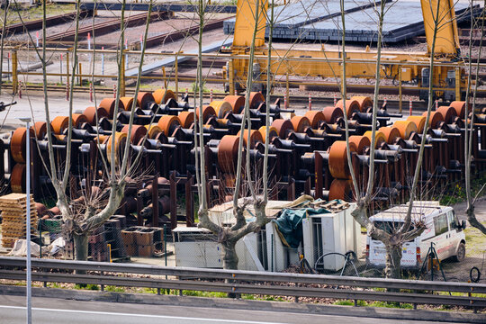 Olaberria, Spain - 09 March 2026: Aerial view of rows of rusty metal rollers stacked high under the watchful gaze of yellow cranes, a scene of industrial strength and weathered beauty..