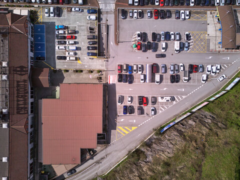 Olaberria, Spain - 09 March 2026: Aerial view of a Carrefour parking lot, where organized rows of cars contrast with the rugged, rocky terrain, bathed in the sun's warm glow.