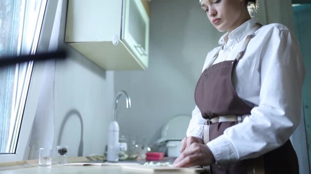 A female chef cooks in the kitchen at home wearing a chef's costume
