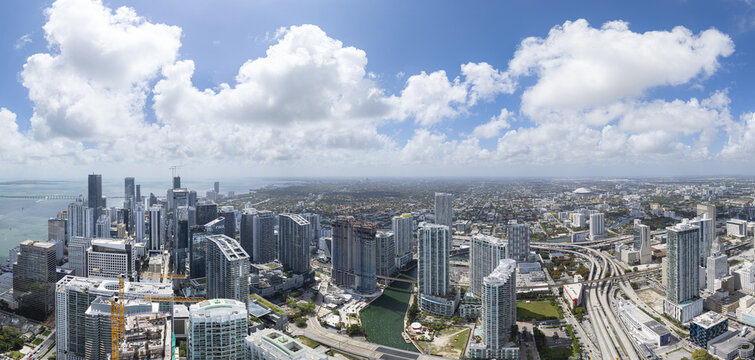 Aerial view of the Miami River snaking through the heart of Brickell's towering skyscrapers under a vast, cloud-dappled sky, Miami, Florida, United States.