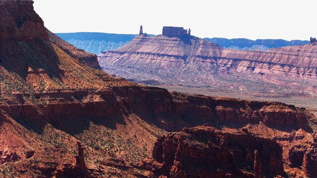 Aerial view of the majestic buttes and mesas sculpt the horizon, casting deep shadows across the rugged landscape, a symphony of red rock formations, Moab, Utah, United States.