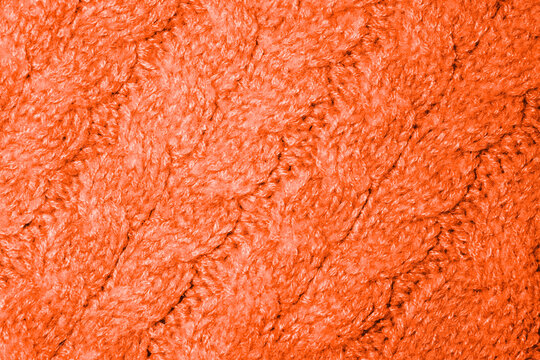 Close-up view of soft orange knitted texture with intricate patterns and warmth