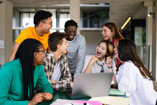 A Diverse Group of Friends is Actively Collaborating and Laughing Together in a Modern Workspace