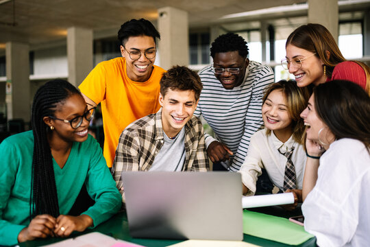 A Diverse Group of Friends Collaborating Actively on a Laptop in a Stylish Modern Workspace