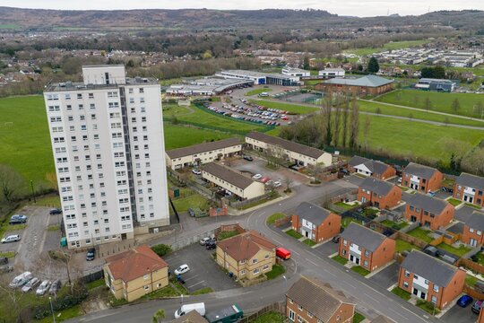 Aerial view of the Middlesbrough housing estate with a tower block roads and green fields showing urban layout and nearby school buildings from above in the spring season in the daytime