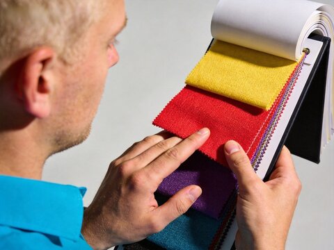 Man touches colorful fabric swatches in sample book