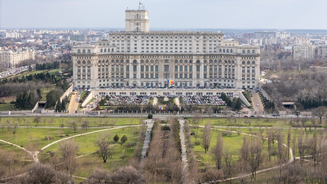 Aerial view of the colossal Palace of the Parliament, a stark white monolith rising from the green expanse of the park, Bucharest, Bucuresti, Romania.