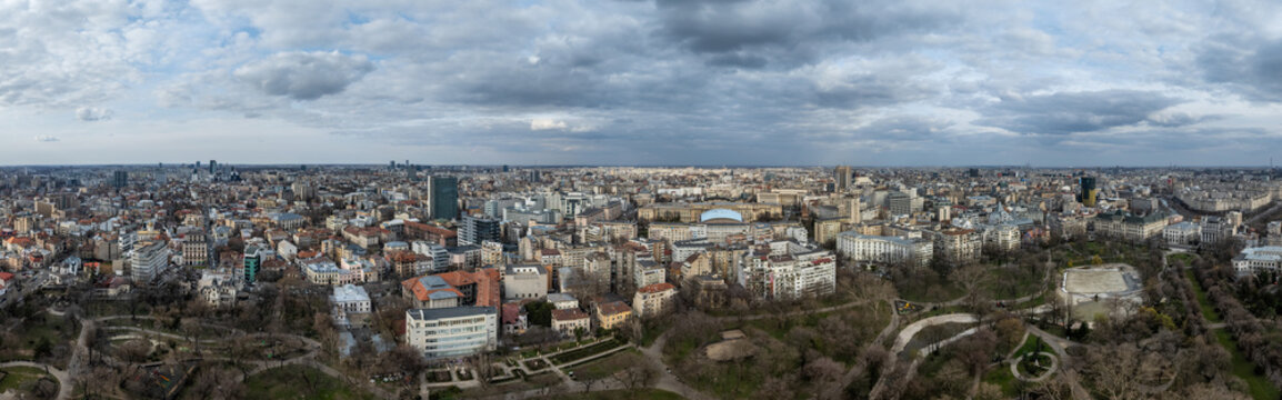 Aerial view of Bucharest's urban sprawl under a cloudy sky, where buildings meet the bare trees of a sprawling park, Bucharest, Bucharest, Romania.