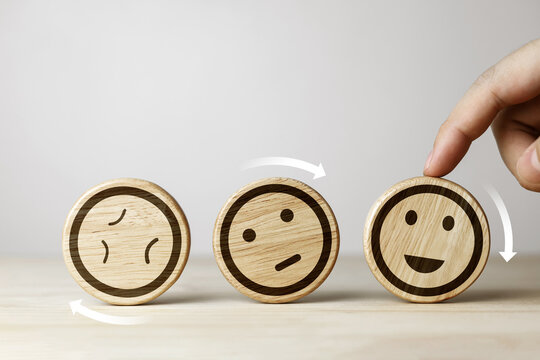 A rotating wooden panel displaying changing facial expressions. concept of attitudes towards positive change, improving customer service, and increasing satisfaction in the evaluation process.