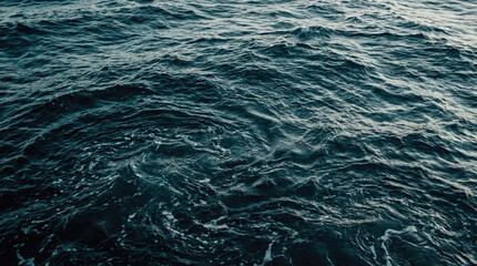 Obraz premium Dark ocean waves shimmer with deep blue hues. Ripples on the surface. Foam swirls, waves meet with the sea element. Rough texture of water