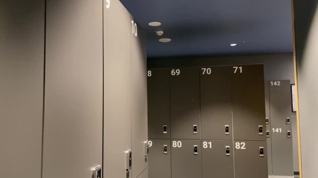 Numbered changing cubicles in a public locker room, gray interior with no people, emphasizing order, privacy, and minimal design. Changing room interior.