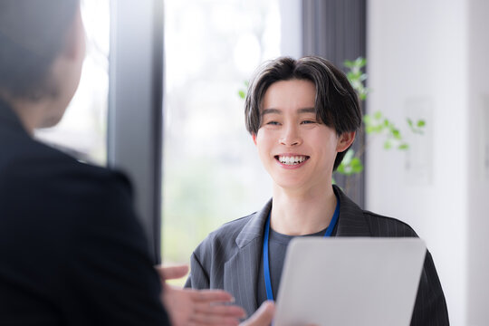 仕事での面談やキャリアカウンセリングなど対面で面接する爽やかなビジネスイメージ　デザイナーやエンジニア、マーケターなどクリエイティブ職のインターンなど新卒の若い男性