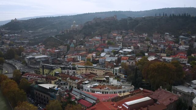 Aerial view of Old Tbilisi, Georgia with colorful rooftops, historic churches, Narikala Fortress on the hill, and dense urban architecture. Scenic panorama captures authentic Caucasus atmosphere.