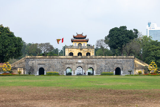 View of the ancient citadel with its weathered stone walls and vibrant flags fluttering against a backdrop of modern skyscrapers, Hanoi, Ha Noi, Vietnam.