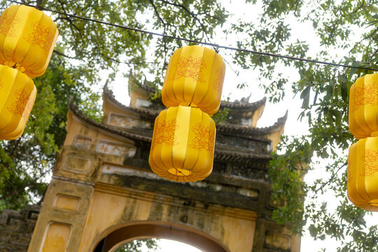 View of golden silk lanterns casting a warm glow against the weathered stone archway, a fusion of ancient architecture and vibrant color, Hanoi, Ha Noi, Vietnam.