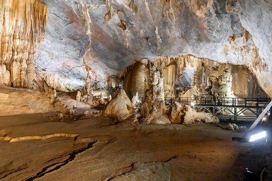 View of the cave's interior with dramatic rock formations, enhanced by the soft glow of artificial lights, creating a surreal landscape, Paradise Cave, Quang Binh, Vietnam.