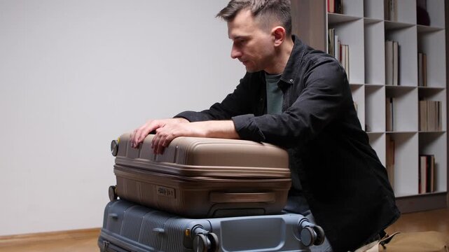 Man organizes belongings in a lightweight hard shell wheeled suitcase inside a bright hotel room, packing or unpacking for a weekend getaway, business trip, or holiday journey