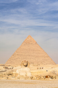 View of the majestic pyramid and the iconic Sphinx basking in the warm desert sun against a backdrop of clear blue skies, Giza, Egypt.
