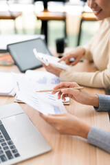 Fototapeta premium Business team hands analyzing financial growth charts and using calculator during strategy planning at a modern wooden desk in office.