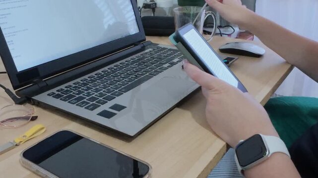 Modern portable office setup with hands using a tablet, alongside a laptop and other essentials.