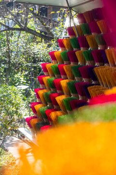 View of vibrant bundles of incense sticks stacked in a pyramid of colors, a fragrant spectacle under the sunlit trees, Hue, Vietnam.