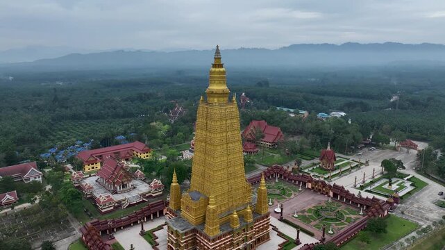 Aerial view of the golden Wat Maha That Wachiramongkol temple complex amid lush greenery, creating a striking contrast of color and form, Kho Phi Phi Island, Thailand.