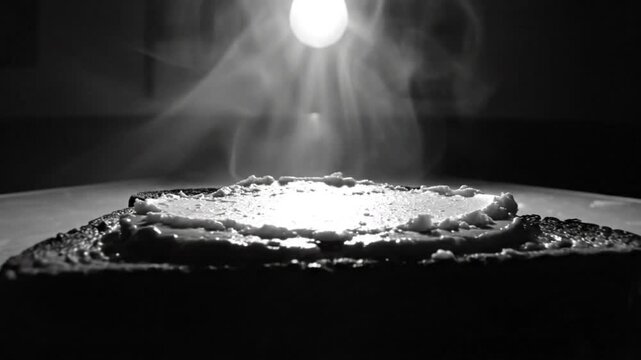 Black and white close up of buttered toast with smoke and a light bulb creating a dramatic scene