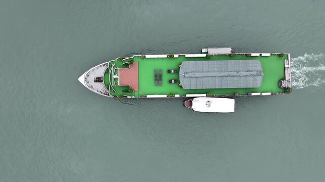 Aerial view of a boat cruising on the tranquil water, its wake creating a rippling pattern on the surface, Halong Bay, Vietnam.