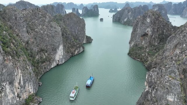 Aerial view of the emerald waters weaving between towering limestone karsts, their rugged textures contrasting with the smooth sea, Halong Bay, Vietnam.