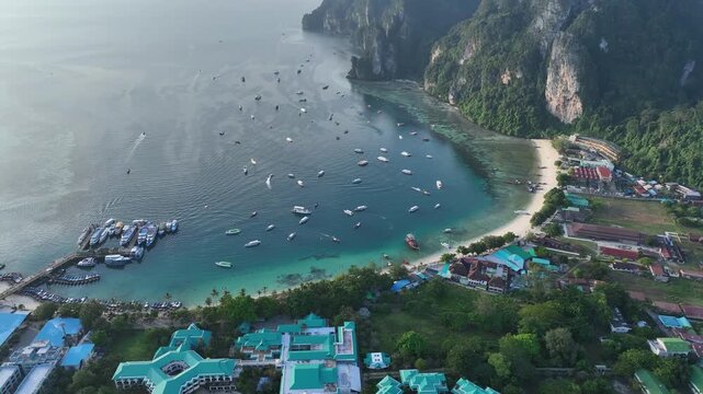 Aerial view of numerous boats scattered across the turquoise bay, contrasting against the lush green landscape of Halong Bay, Vietnam.