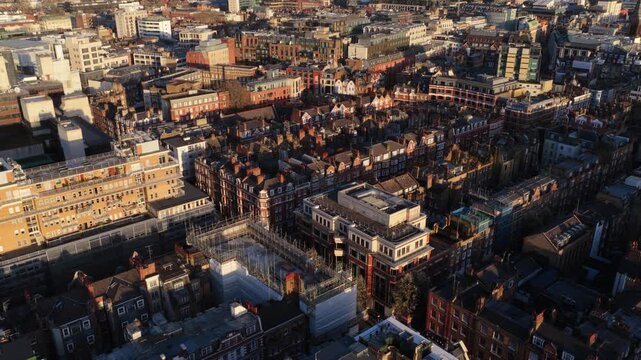 Aerial shot of London's historic neighborhoods during a sunny day, showcasing classic brick buildings and intricate street layouts and city's unique urban character