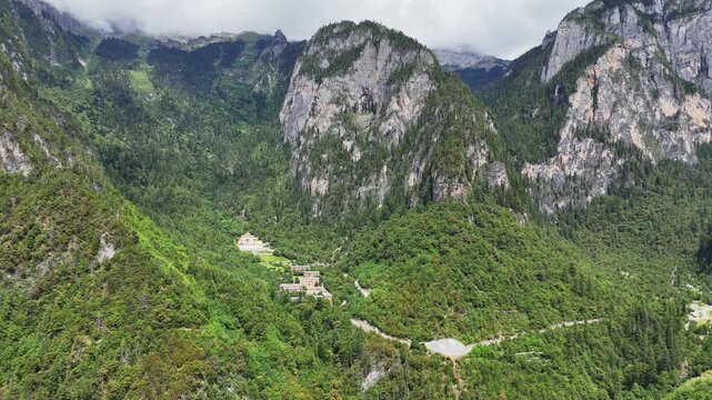 Breathtaking aerial shot of the lush green Balagezong Grand Canyon mountains and a remote Tibetan village nestled in the valley of ShangriLa, Yunnan.