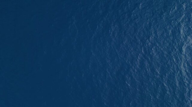 Top down aerial drone shot of ocean surface with detailed ripple patterns and tropical blue tones