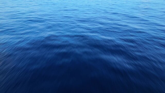 Drone aerial shot of flat ocean surface with glassy reflections and dark storm clouds overhead