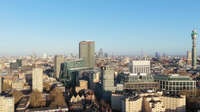 Urban panorama showing London cityscape with BT Tower, modern architecture, business district skyscrapers, and residential neighborhoods under a clear blue sunny sky