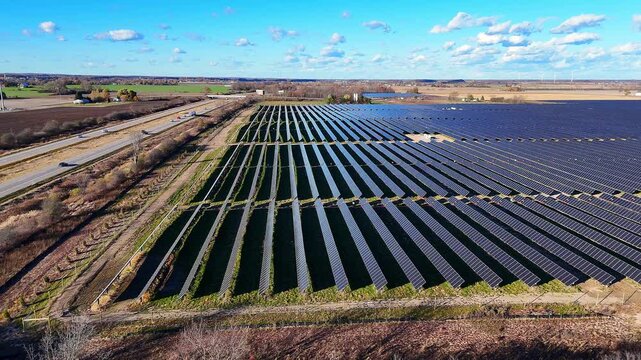 Solar panels generating clean energy on a vast field in Ithaca, Michigan next to US127 highway