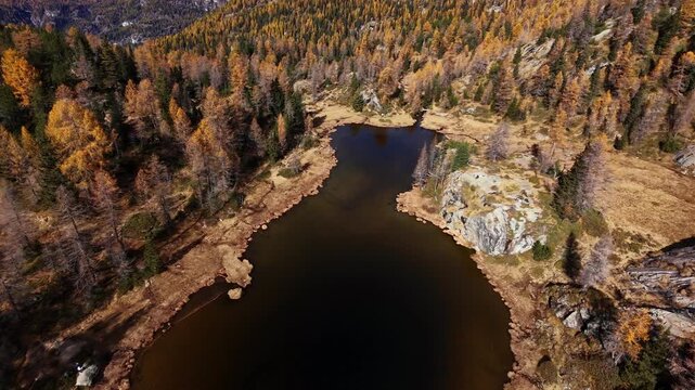 Aerial View Of Lago Mufule In Sondrio, Italy - Dark Alpine Lake Surrounded By Autumn Trees. FPV orbiting drone shot