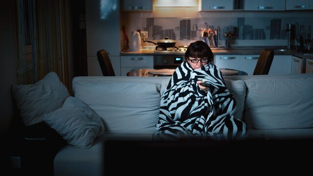 Woman Watching TV Wrapped in Blanket in Living Room at Night, have fun and enjoy