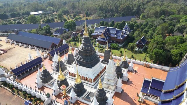 Aerial view of the ornate Wat Phra Kaew temple complex with its tiered roofs and golden spires contrasting with the lush greenery, Wat Phra Kaew, Thailand.