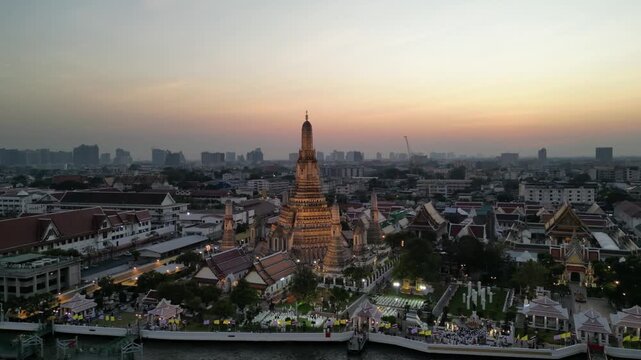 Aerial view of the majestic Wat Arun temple rising above the cityscape, its intricate details contrasting with the soft hues of the twilight sky, Wat Phra Kaew, Thailand.