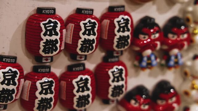 Traditional Japanese tourist souvenirs and gifts from Kyoto, Kansai, Japan, with daruma figures, kitsune fox, tengu mask, fridge magnets, toys figurines, key ring keychain, in a local vendor gift shop