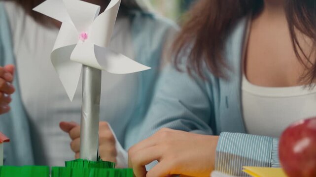 Close up four Caucasian teenage friends discussing origami crafts indoor classroom students group boy three girls talking together learning studying paper heart windmill house handmade school teamwork