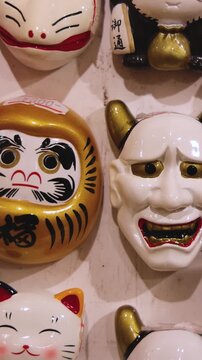 Traditional Japanese tourist souvenirs and gifts from Kyoto, Kansai, Japan, with daruma figures, kitsune fox, tengu mask, fridge magnets, toys figurines, key ring keychain, in a local vendor gift shop