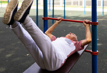 Obraz premium Old man doing leg raise exercise outdoors