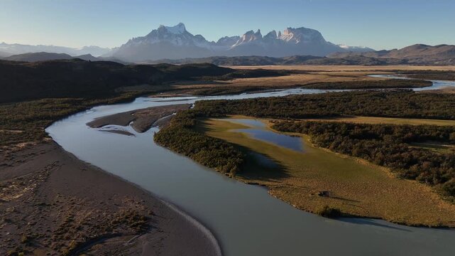Aerial view of a winding river cutting through the landscape with snow-capped mountains in the background, Torres del Paine, Chile.