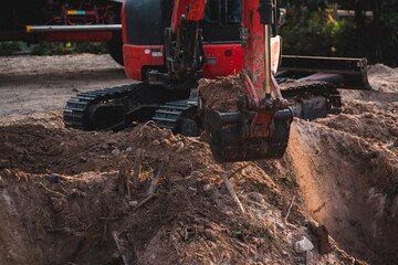 Fototapeta premium Excavator digging soil at construction site. Building foundation and infrastructure project